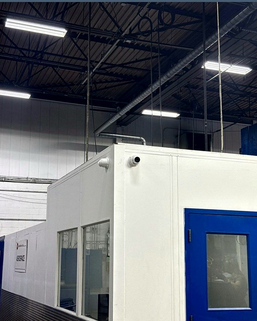 Corner-mounted dome security camera covering the aerospace machining enclosure entrance at the MIBA automotive manufacturing plant in Sterling Heights, Michigan, installed by Michigan Security Systems
