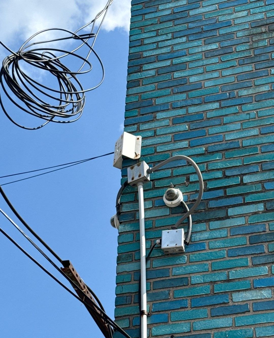Aging dome camera before replacement on a brick commercial building exterior in Michigan — before photo by Michigan Security Systems
