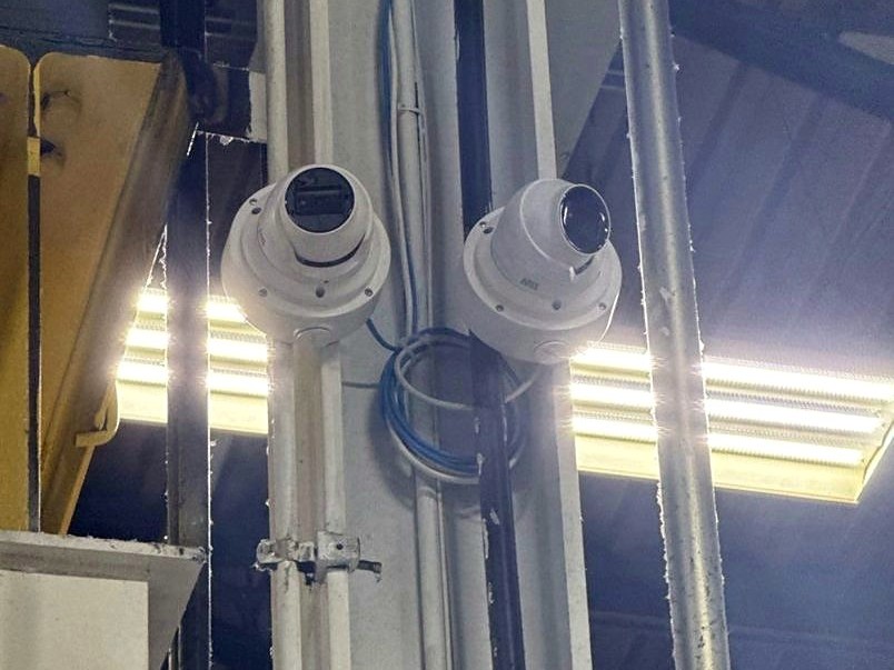 Two Axis Communications turret-dome security cameras mounted on structural piping inside a Michigan commercial facility - installed by Michigan Security Systems