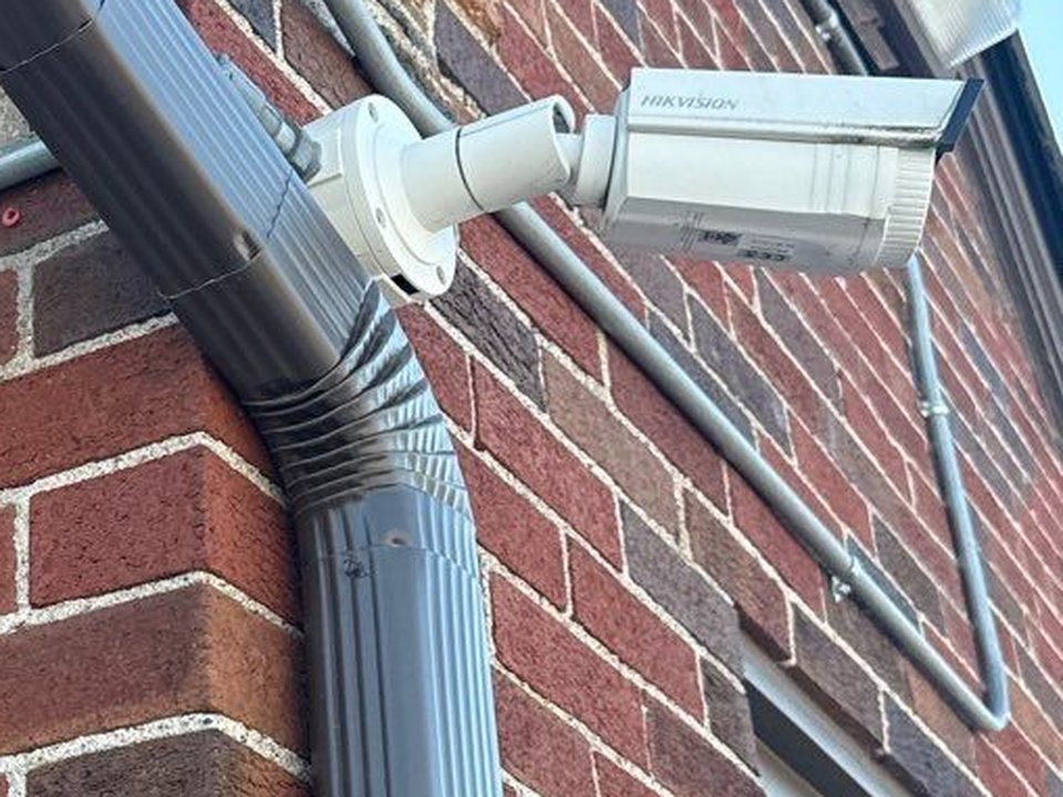 Hikvision bullet camera installed on brick commercial building exterior by Michigan Security Systems in Michigan