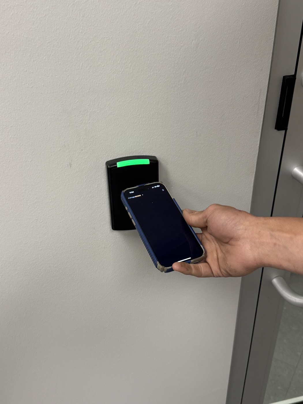 Smartphone mobile credential tapped to an access control reader — Michigan Security Systems