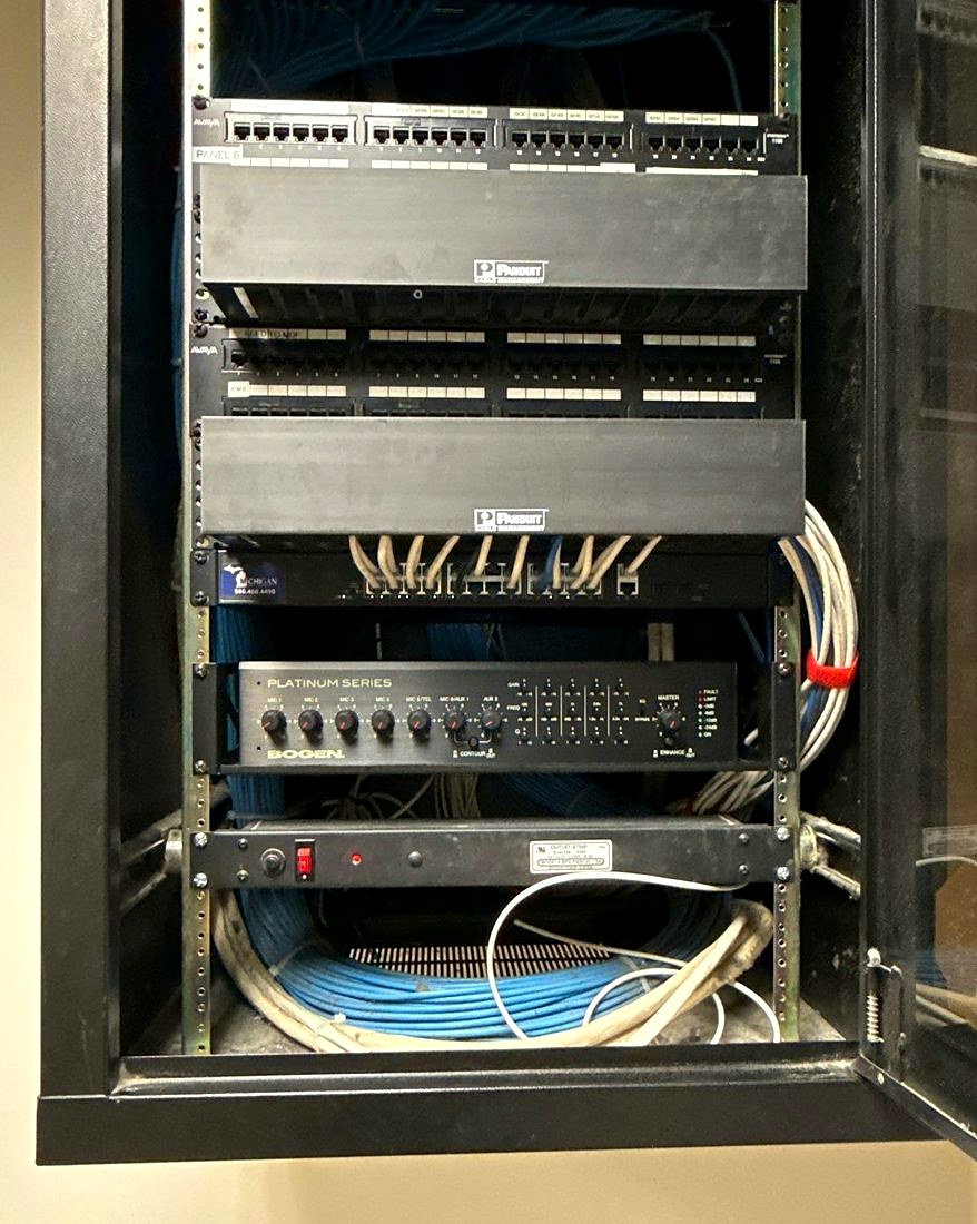 Network rack with Avaya patch panels, Panduit cable management, a Michigan Security Systems managed switch, a Bogen paging amplifier, and structured blue cabling at Care of Southeast Michigan in Fraser, Michigan, installed by Michigan Security Systems