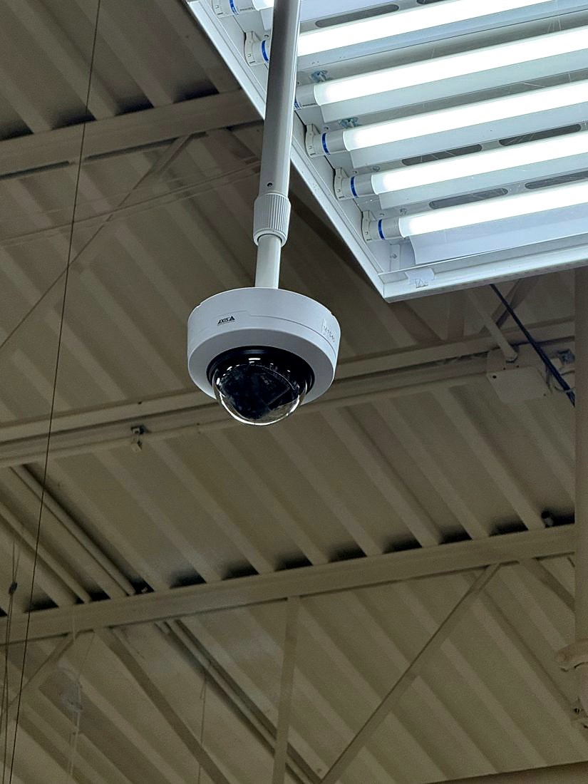 Pendant-mounted Axis dome security camera hanging from the ceiling covering the interior workspace at Merlo Construction in Milford, Michigan, installed by Michigan Security Systems