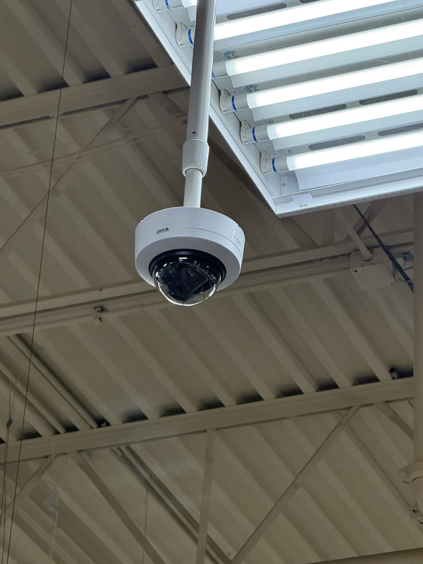 Pendant-mounted Axis dome security camera hanging from the ceiling covering the interior workspace at Merlo Construction in Milford, Michigan, installed by Michigan Security Systems