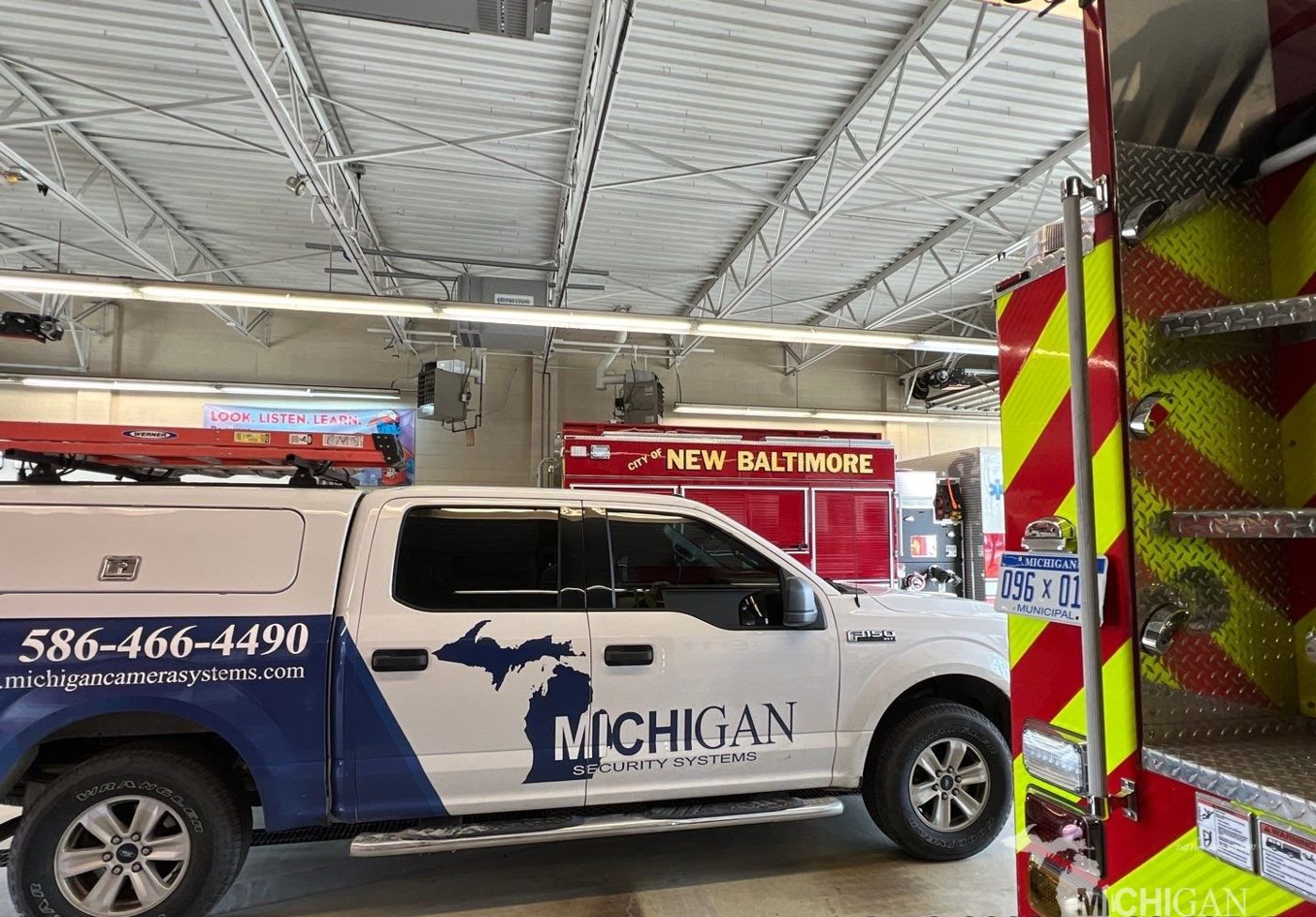 Michigan Security Systems truck inside the City of New Baltimore fire station next to a fire engine