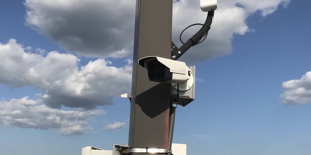 Pole-mounted security camera and wireless radio overlooking a vehicle lot — Michigan Security Systems