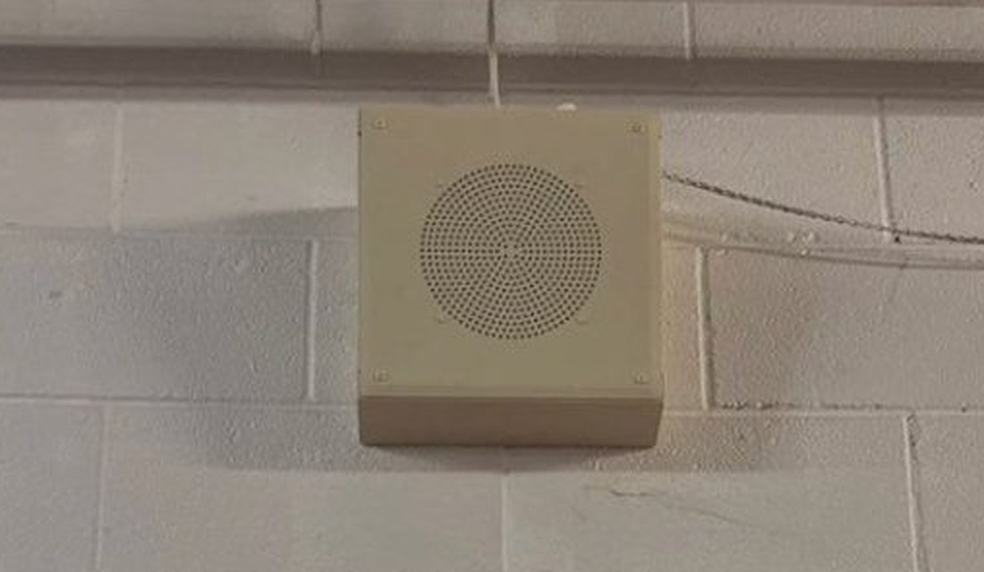 Wall-mounted commercial speaker on a painted block wall above the sales floor at the PTO Thrift Store in Lansing, Michigan, for announcements and background music, installed by Michigan Security Systems