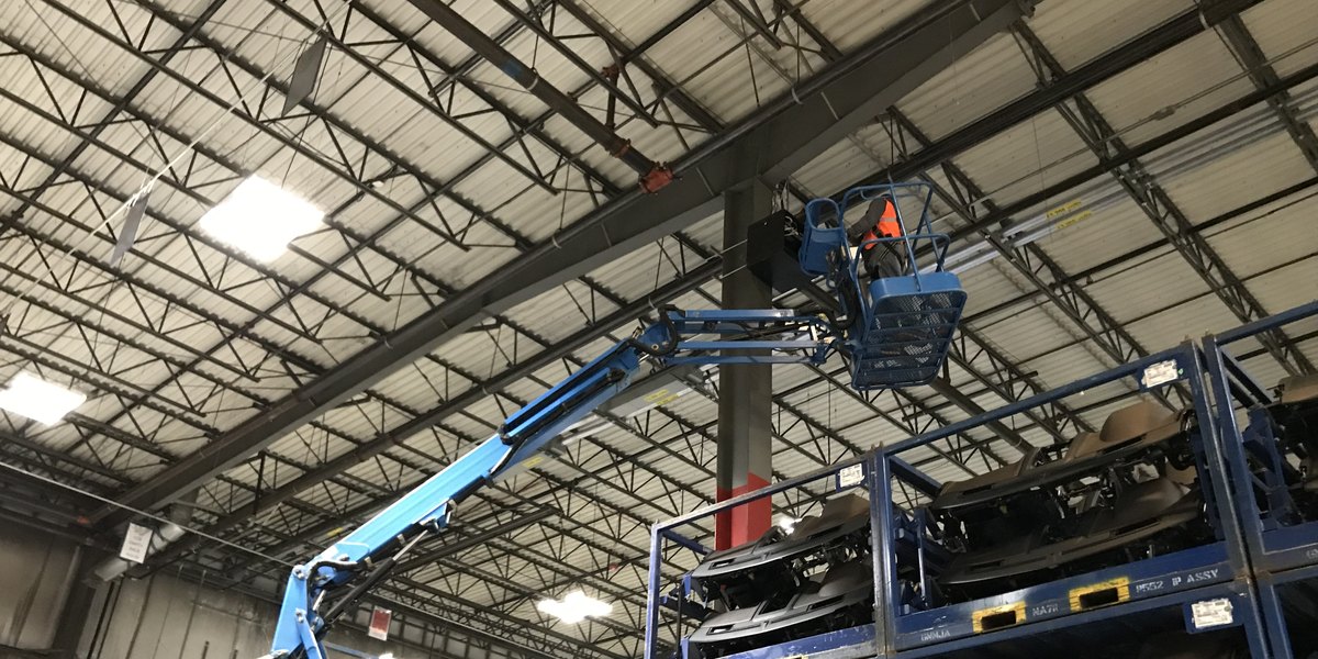 Michigan Security Systems technician on a boom lift installing security cameras in a Michigan manufacturing plant