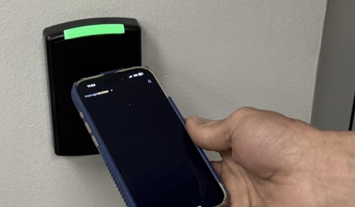 Employee unlocking a commercial door with a smartphone mobile credential — Michigan Security Systems