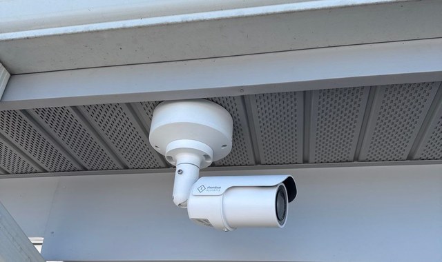 Rhombus bullet security camera mounted under a commercial building soffit — Michigan Security Systems installation
