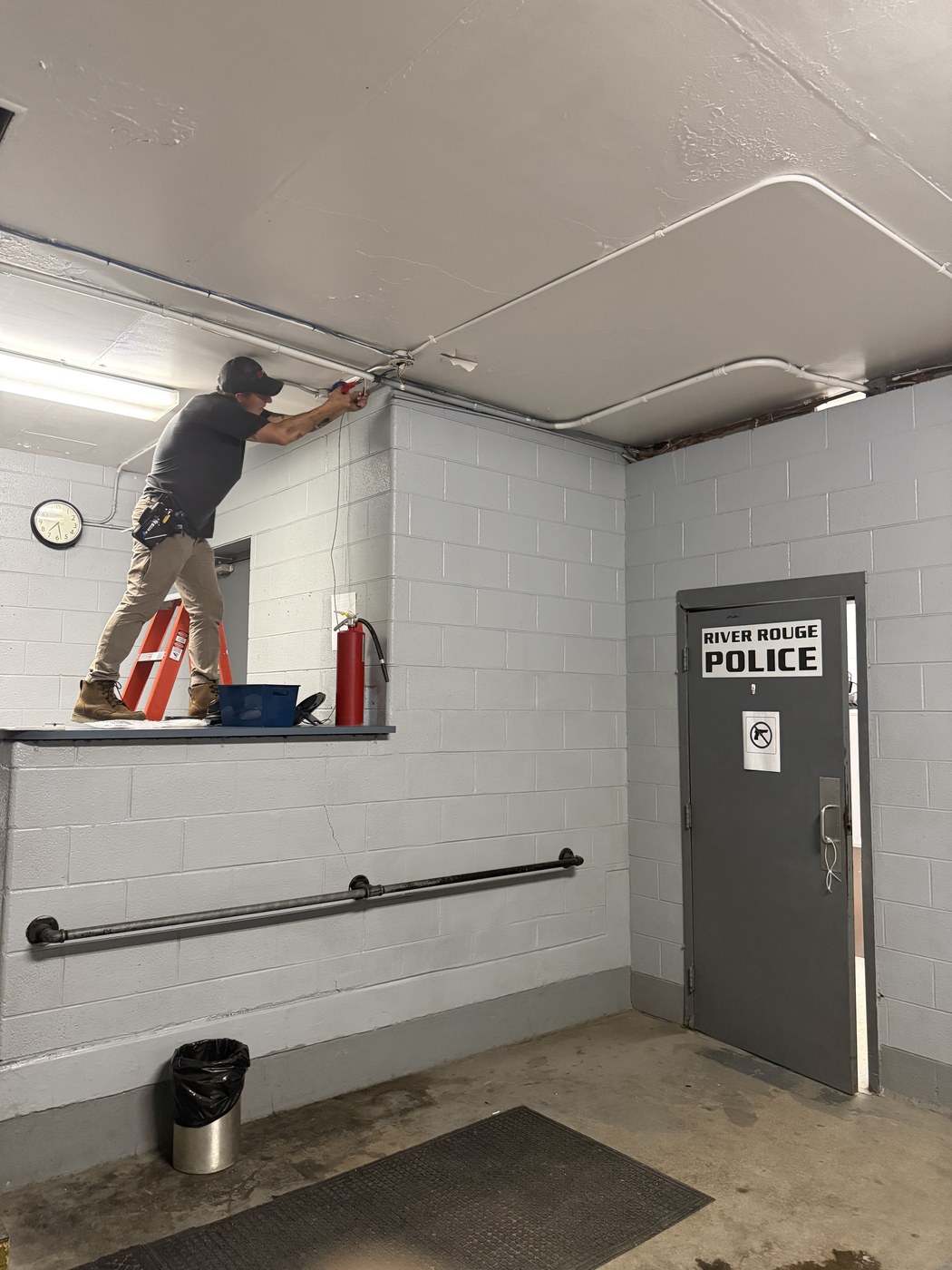 Michigan Security Systems technician working at the River Rouge Police Department entrance during camera system installation