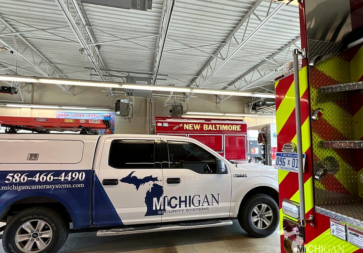 Michigan Security Systems truck inside the City of New Baltimore fire station next to a fire engine
