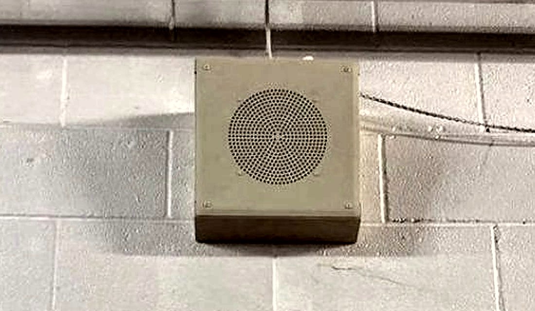Wall-mounted commercial speaker on a painted block wall above the sales floor at the PTO Thrift Store in Lansing, Michigan, for announcements and background music, installed by Michigan Security Systems